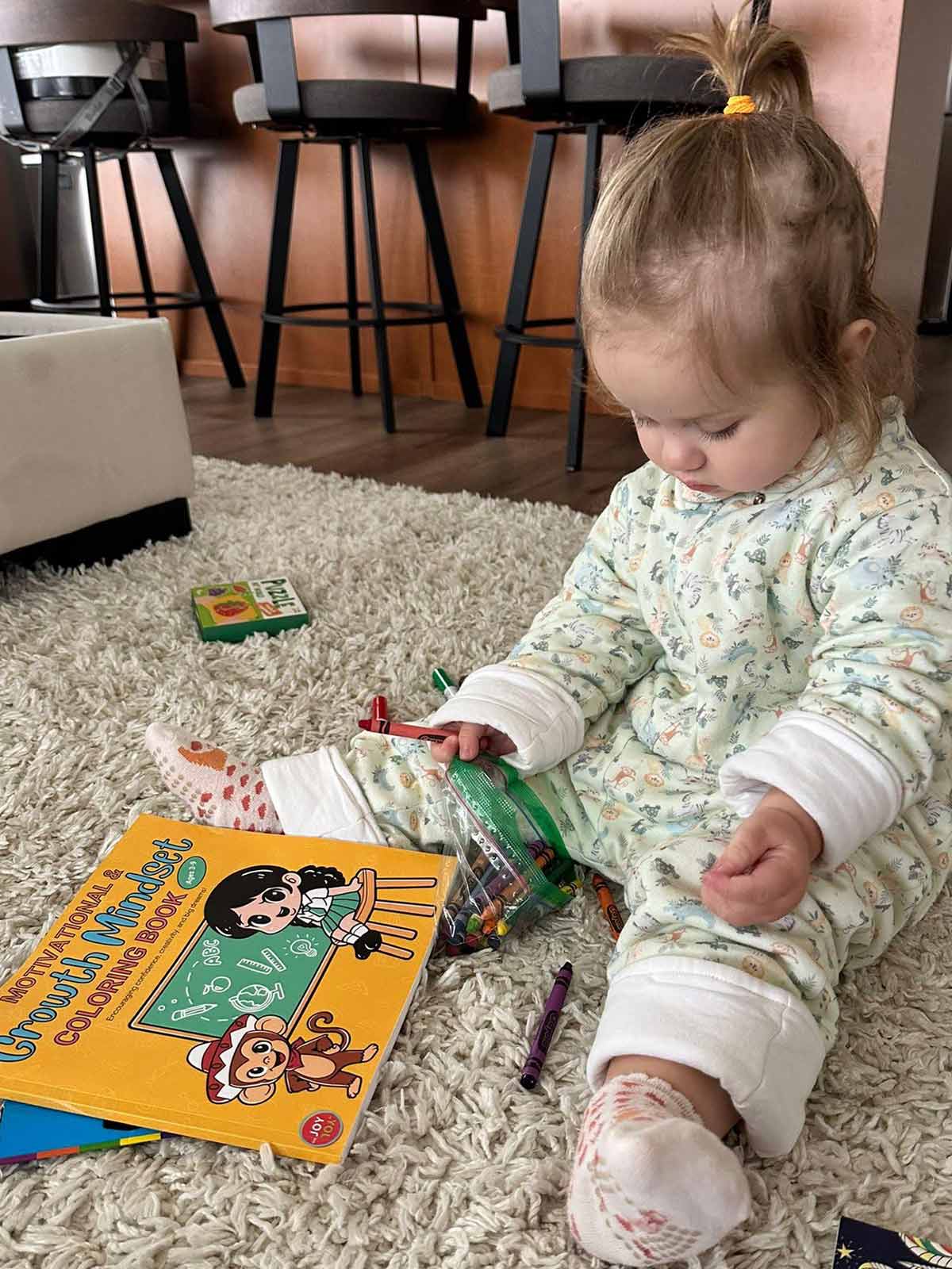 Kid holding The Joy in You coloring book with crayons and markers